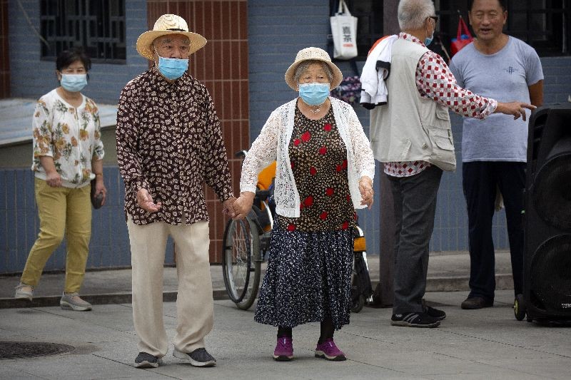 An elderly couple wearing face masks to protect against the coronavirus walks at a public park in Beijing, Saturday, September 12, 2020. Even as China has largely controlled the outbreak, the coronavirus is still surging across other parts of the world. (Photo by Mark Schiefelbein/AP Photo)